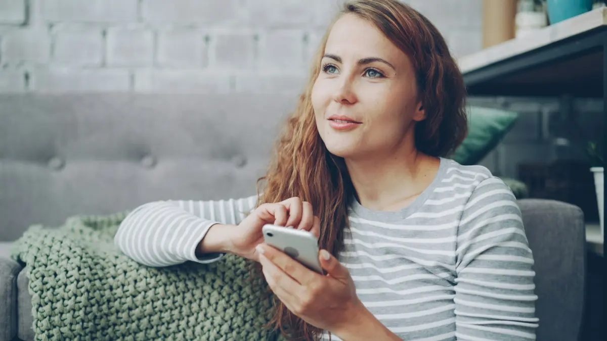 A woman relaxing on a sofa at home with her phone