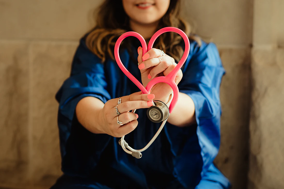 A healthcare worker in blue scrubs holding a stethoscope